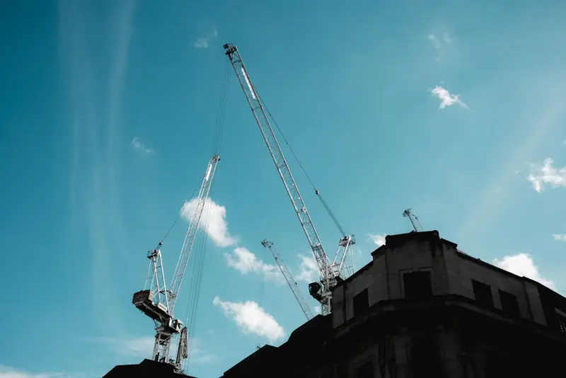 Crane booms reaching into a clear blue sky